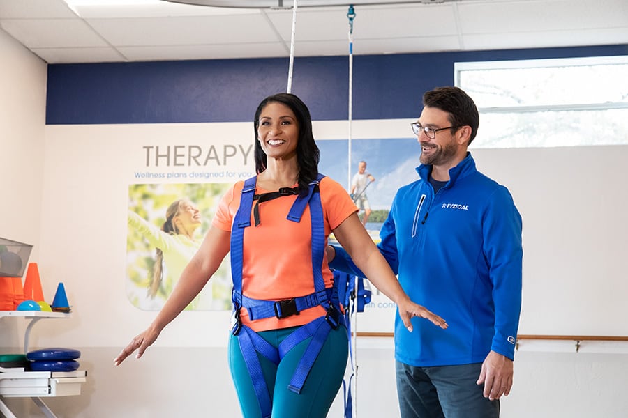 woman on harness walking by physical therapist
